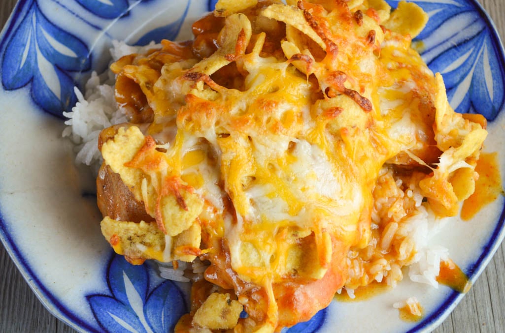 This Cheesy Mexican Chicken is a family-pleasing dinner option with corn chips and cheese on top and served on a bed of rice.