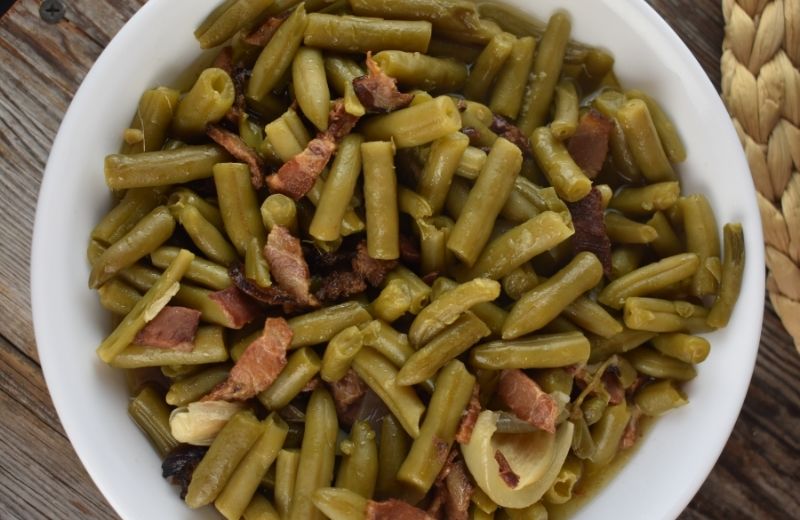 These Crock Pot Green Beans with bacon and onions are easy to make for a crowd. A work pitch-in, family reunion or holiday dinner is not complete without this iconic side dish.