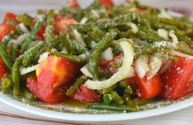 Italian Green Bean Salad is a cold salad featuring thin style green beans, tomatoes and onions tossed in a tasty vinaigrette. A healthy sprinkling of Parmesan cheese takes this salad from good to great. Serve along side grilled chicken for the perfect meal.