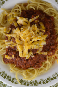 Cincinnati Chili recipe consists of a thick, spicy chili recipe served over spaghetti noodles, and then topped with shredded cheddar cheese.