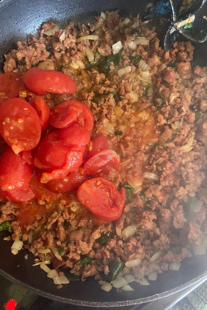 Add stewed tomatoes to the pork sausage mixture.