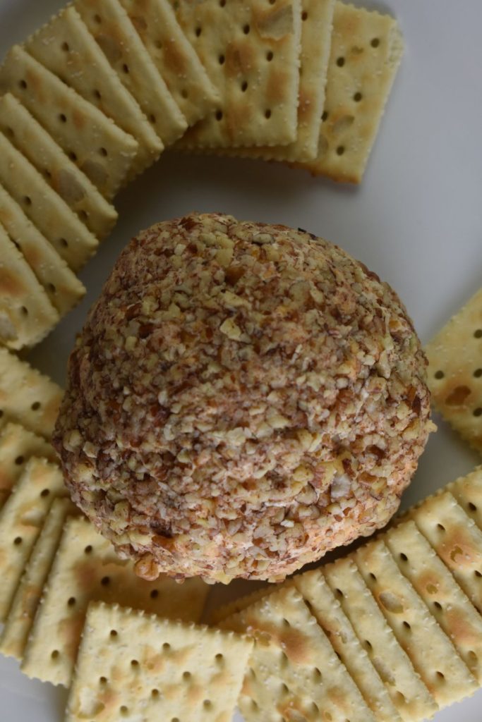 Crackers surrounding a cheese ball covered in nuts