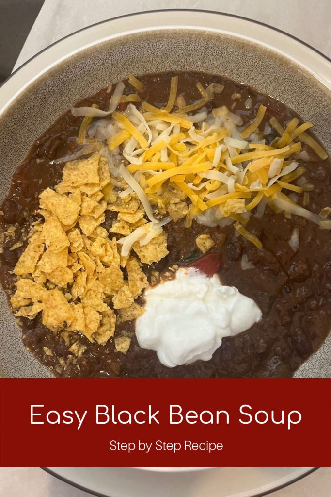 Bowl of Creamy Black Bean Soup topped with sour cream, corn chips and cheese