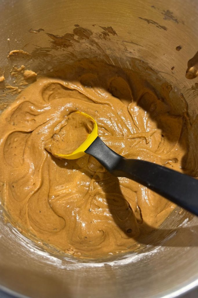 batter for Coffee Chocolate Chip Walnut Muffins in metal mixing bowl with spatula before adding chocolate chips and walnuts