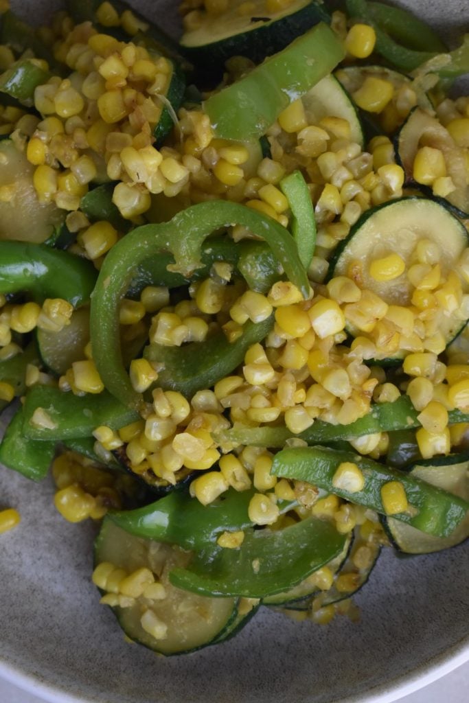 zucchini and corn skillet with sliced green peppers on a plate